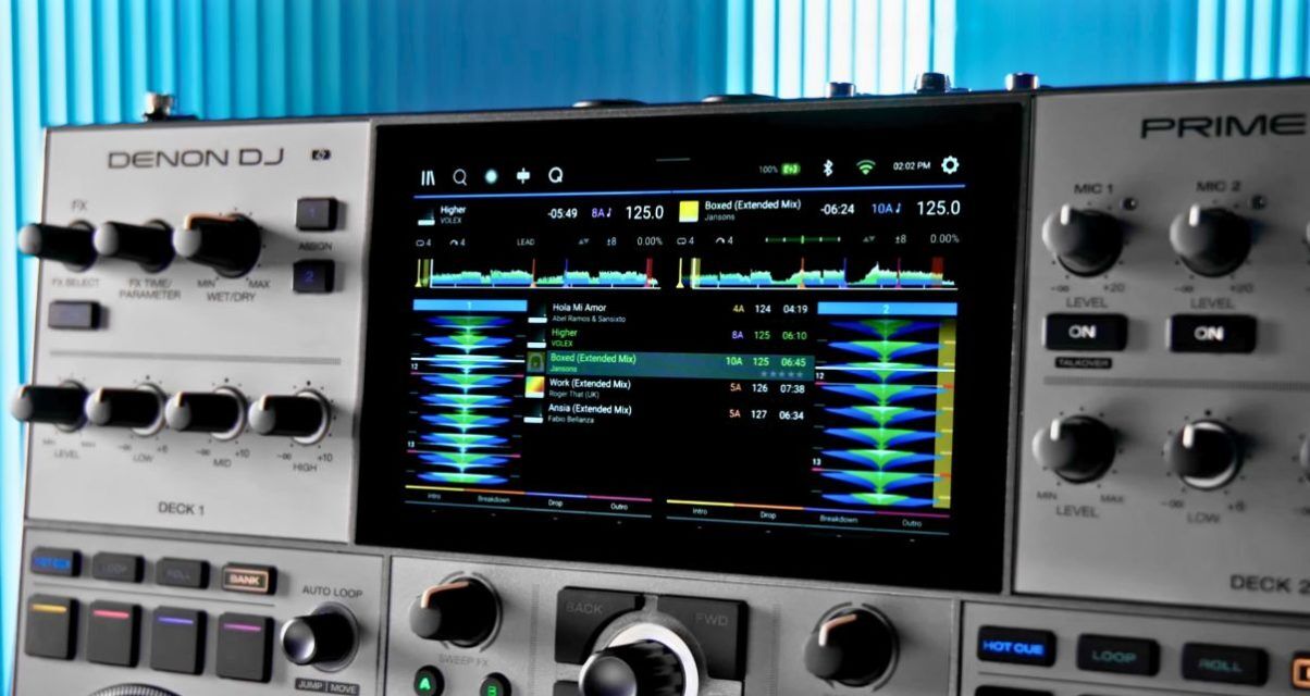 A grey Denon DJ Prime Go+ DJ system with Engine DJ 4.1 software standing up with blue and white lighting in the background