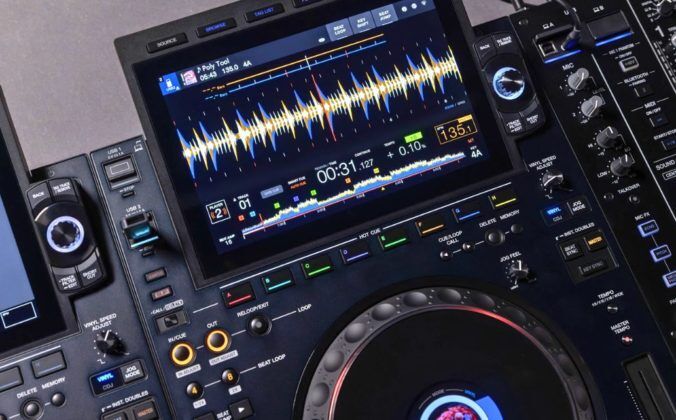 Close-up of an AlphaTheta CDJ-3000x media player featuring dual screens displaying waveforms, track info, and various control buttons for mixing.