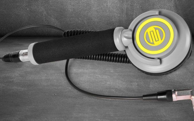 A single Reloop RHP-10 Mono Neon headphone laying flat against a concrete background. The headphones have black, light grey, and bright yellow colouring.